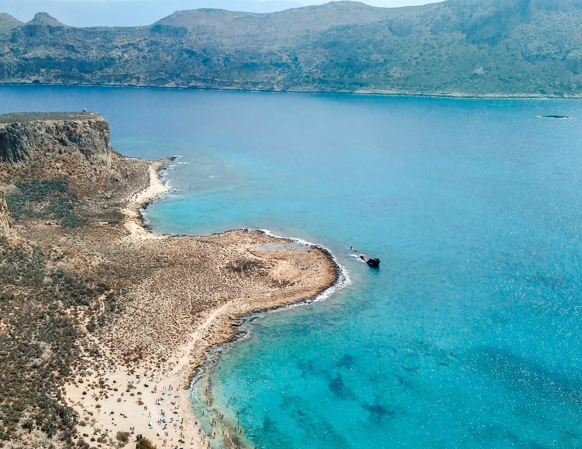 Turquoise baai met een smalle zandstrook gezien van bovenaf